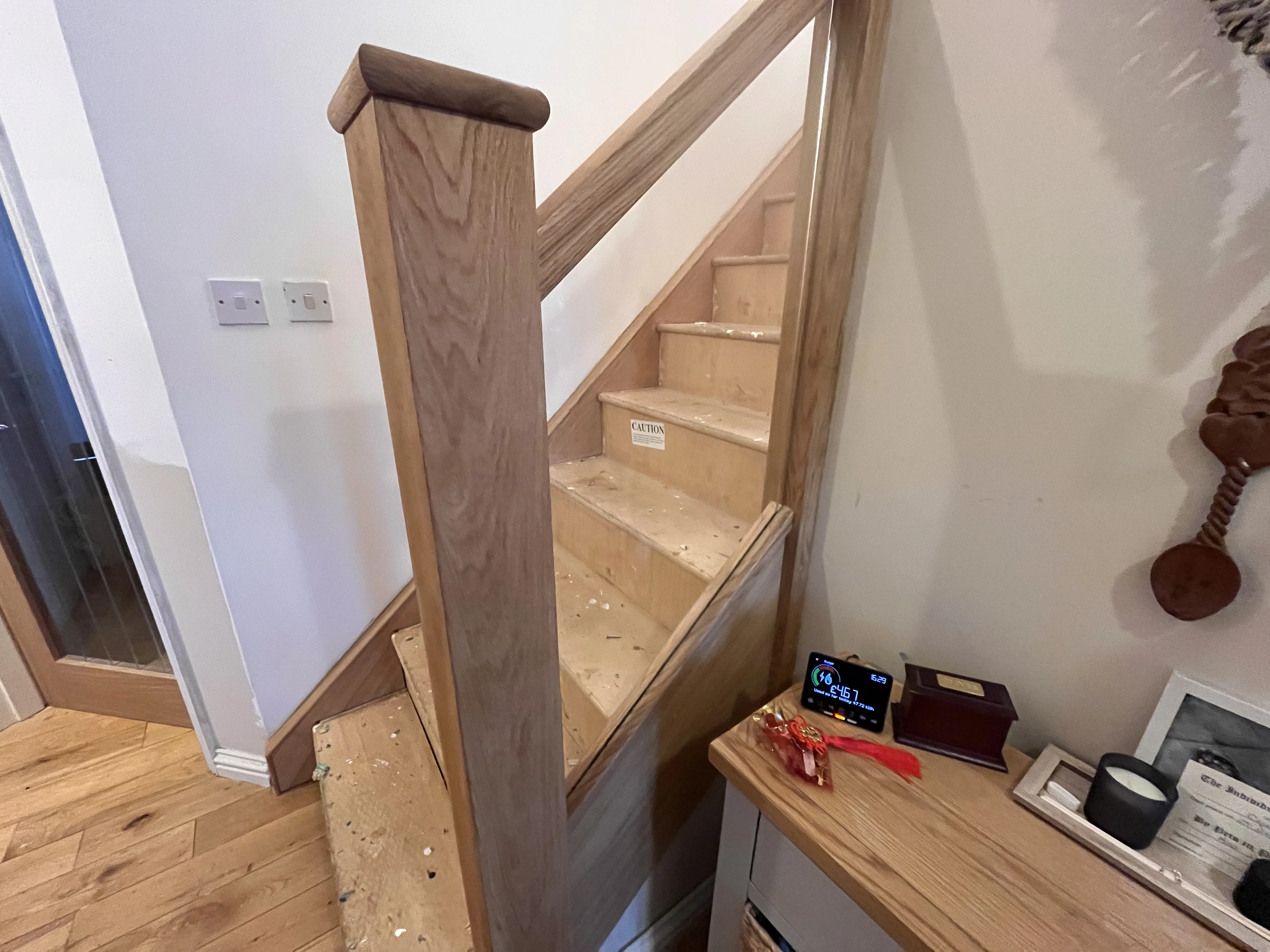 Close-up of an oak-clad newel post with oak cap and glass balustrade panel