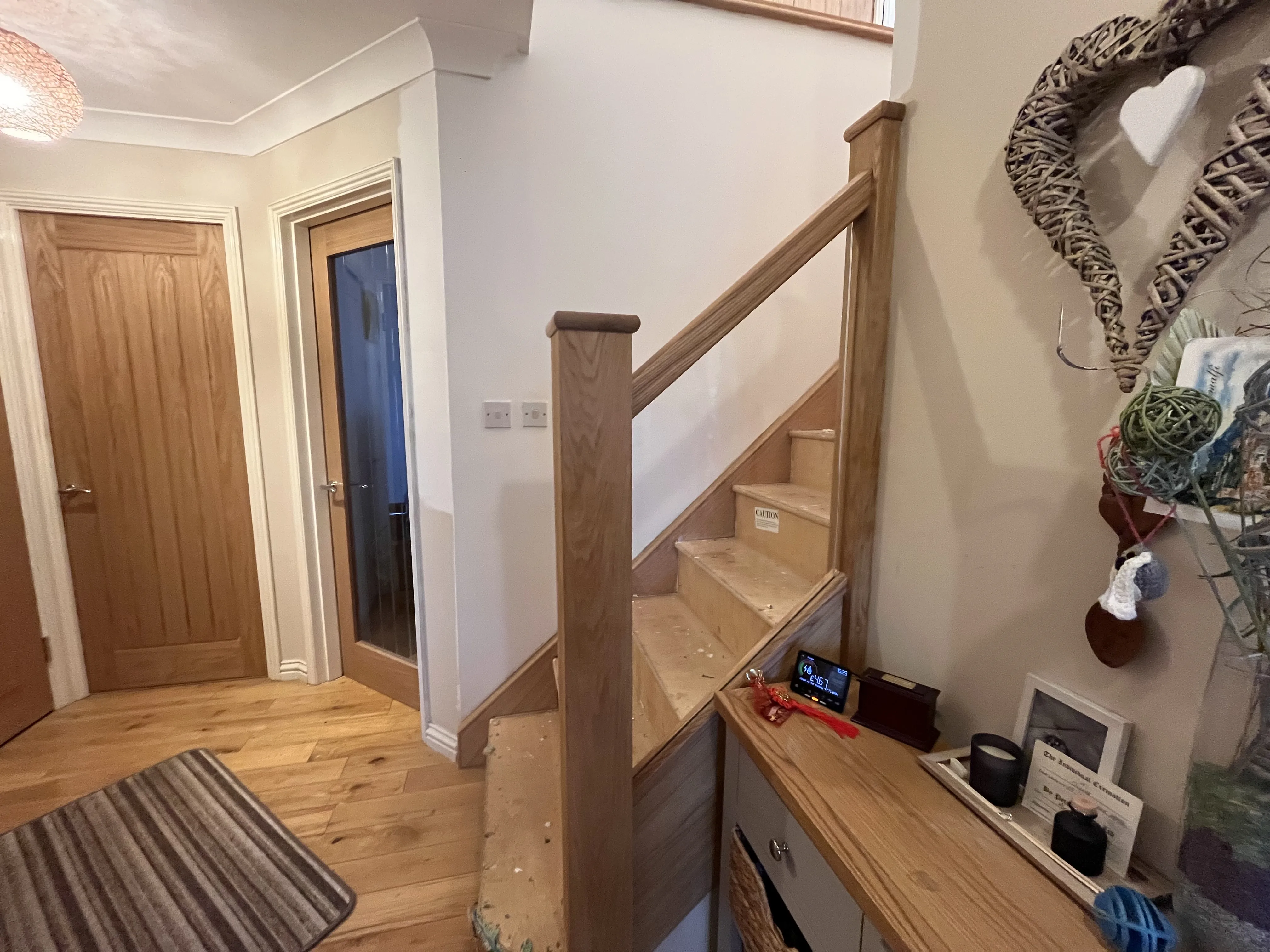 Oak newel post and glass balustrade being fitted in a hallway in Neath Port Talbot