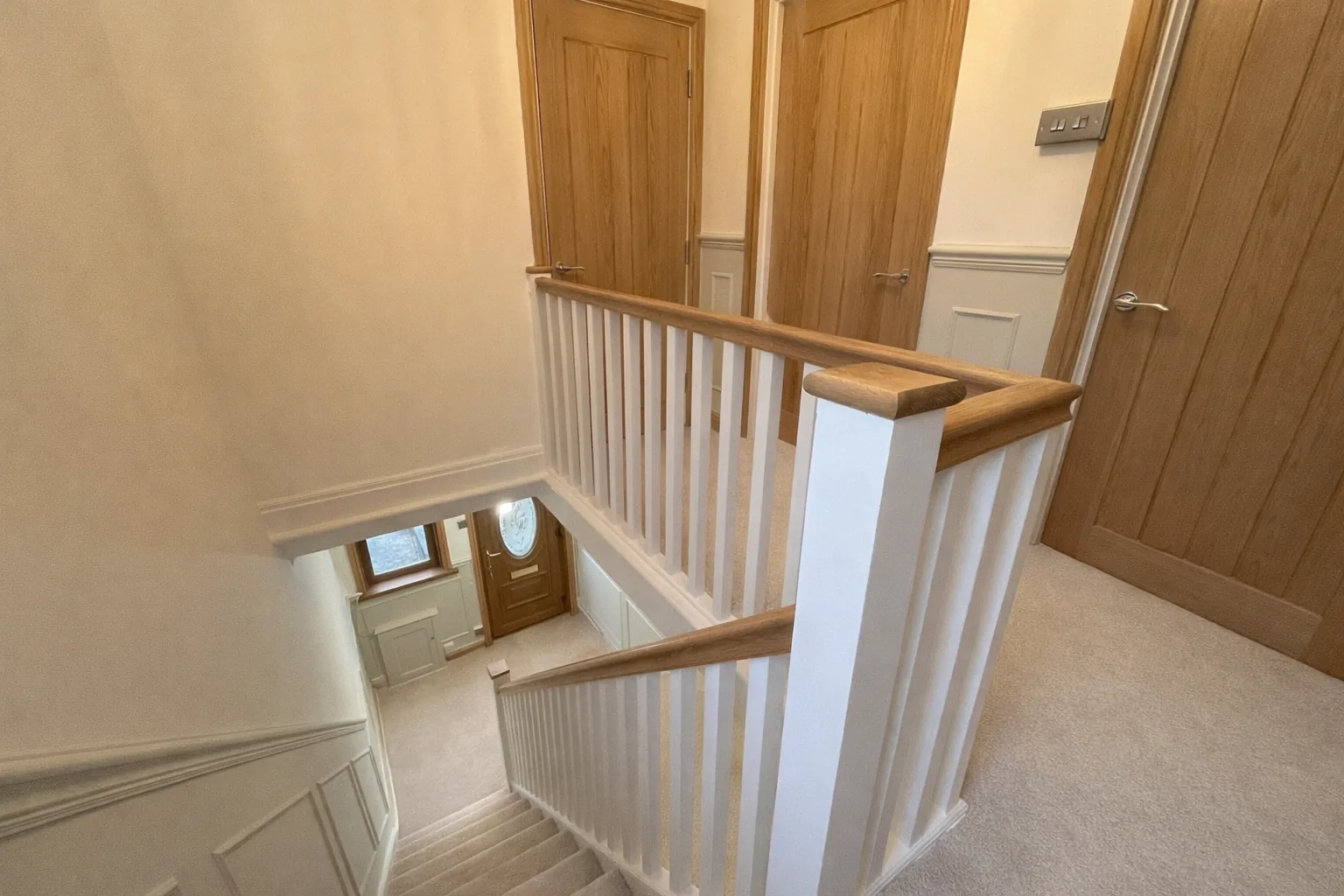 Landing balustrade with oak handrail, oak newel caps and white spindles