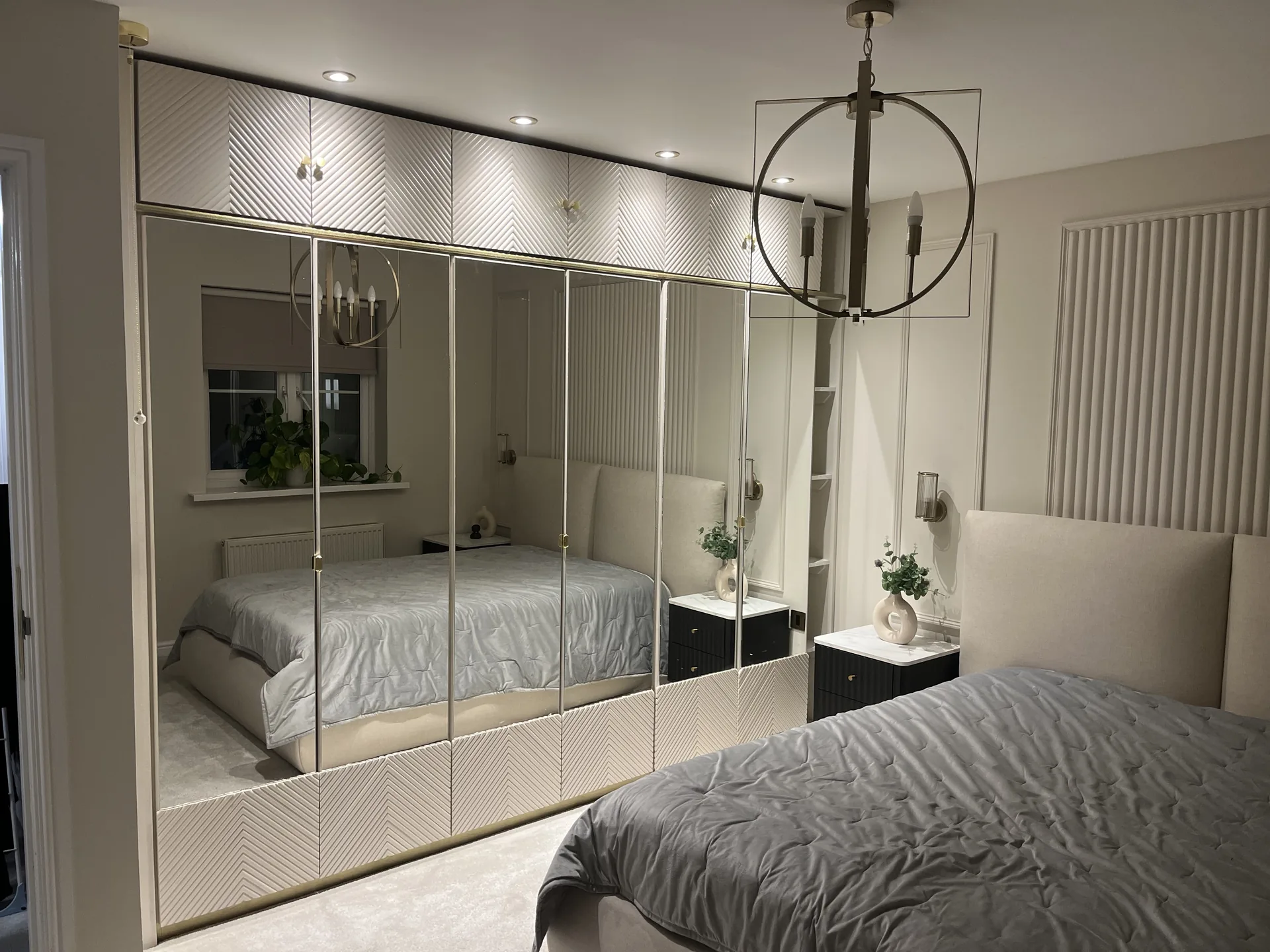 Full-wall fitted wardrobe with mirrored doors and spotlights by LM Carpentry