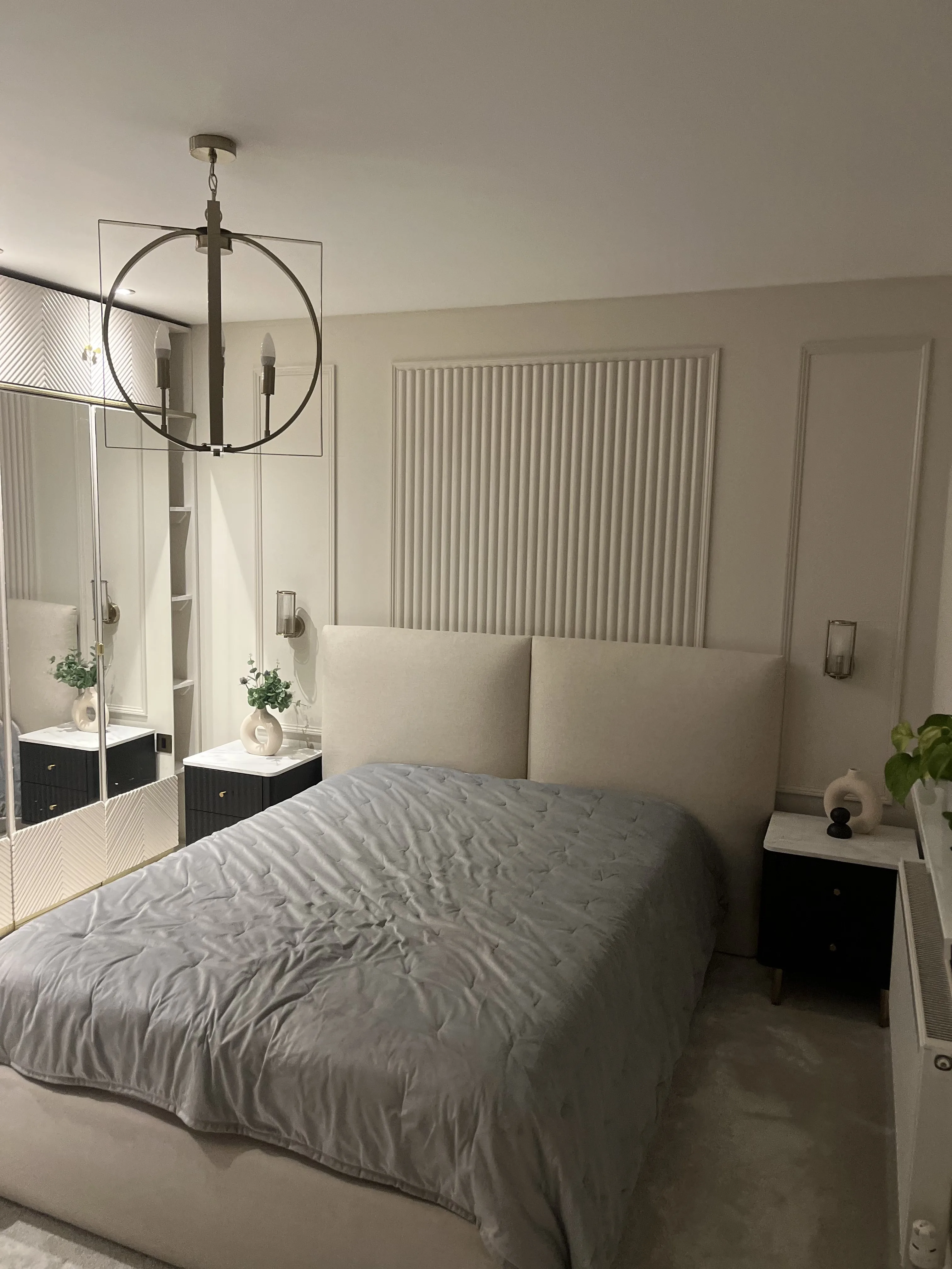 Bedroom with a mirrored fitted wardrobe beside a panelled feature wall