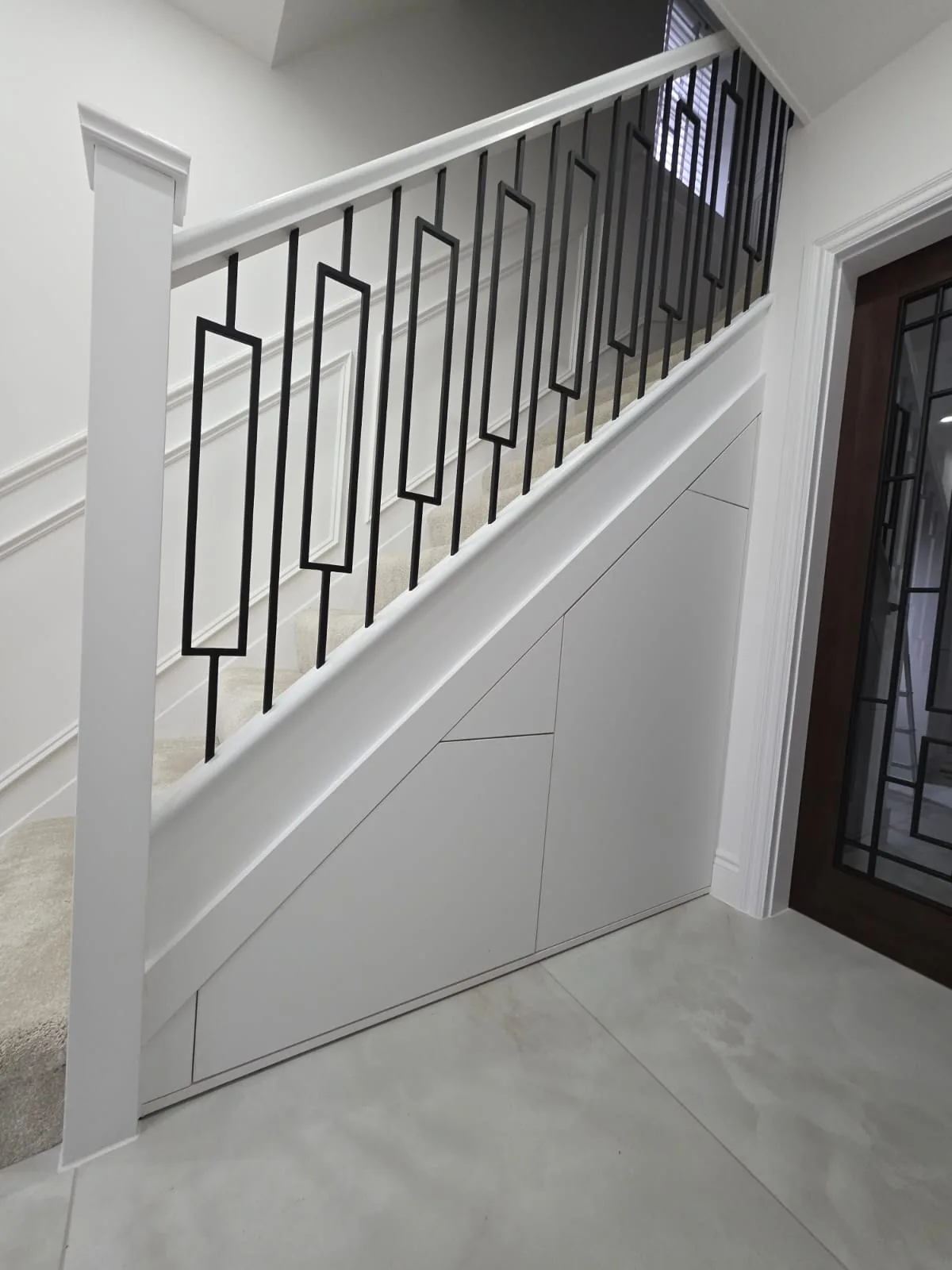 White under stairs storage beneath a staircase with a black metal balustrade