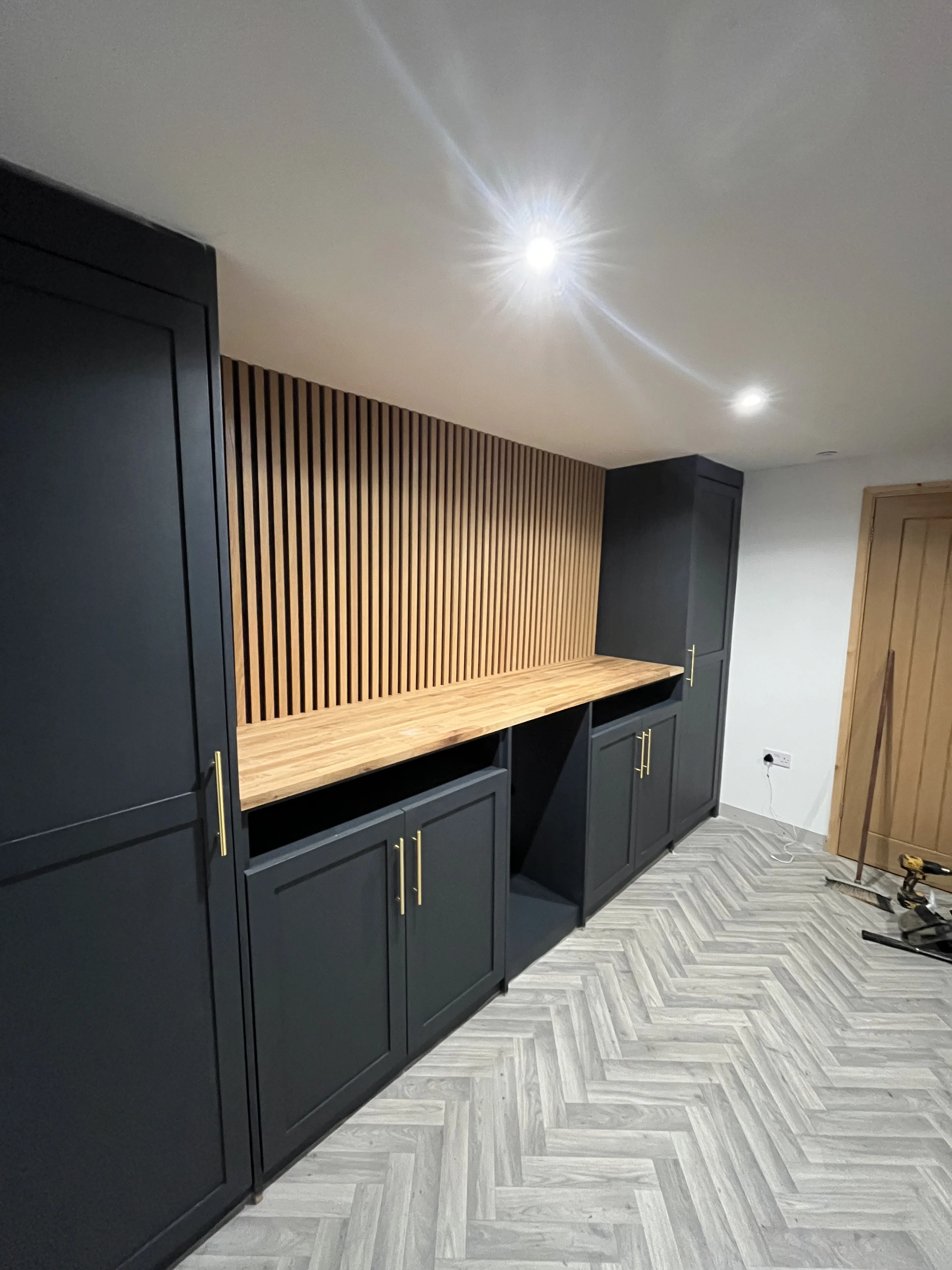 Bespoke media wall with dark grey cabinetry and oak slat panel