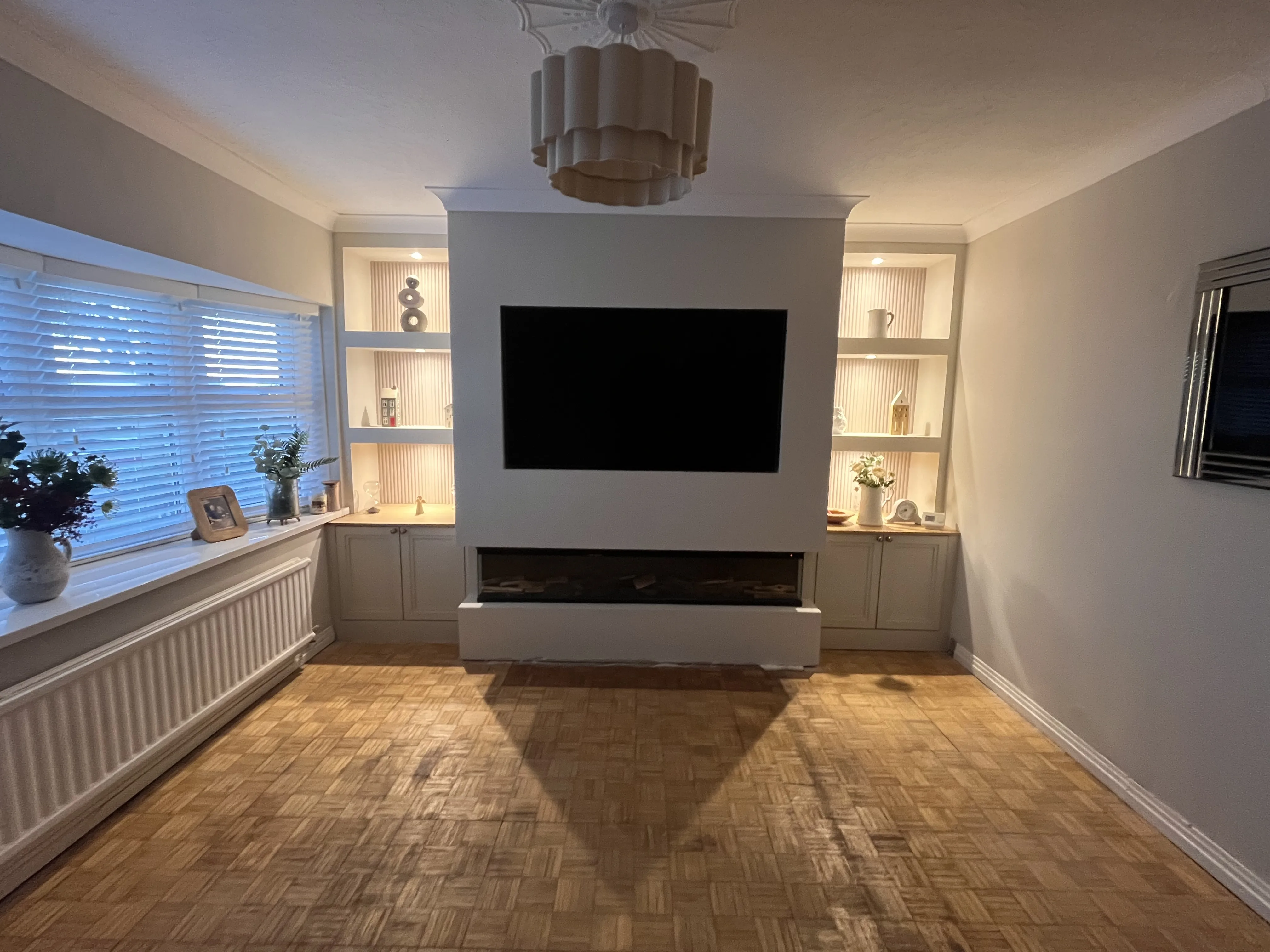Bespoke media wall with white alcove shelving and electric fireplace in Swansea