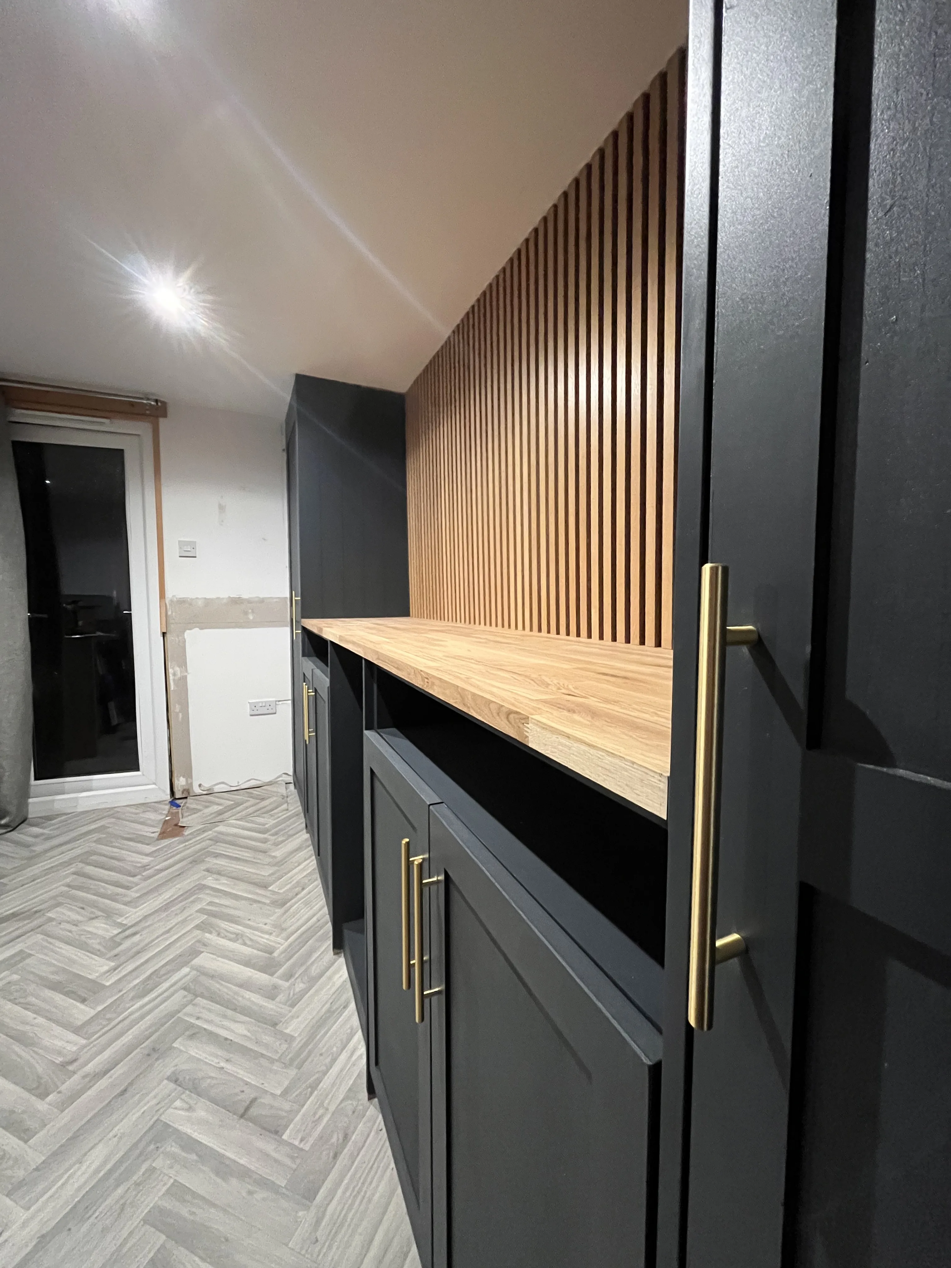 Media wall with dark grey cabinetry and brass handles