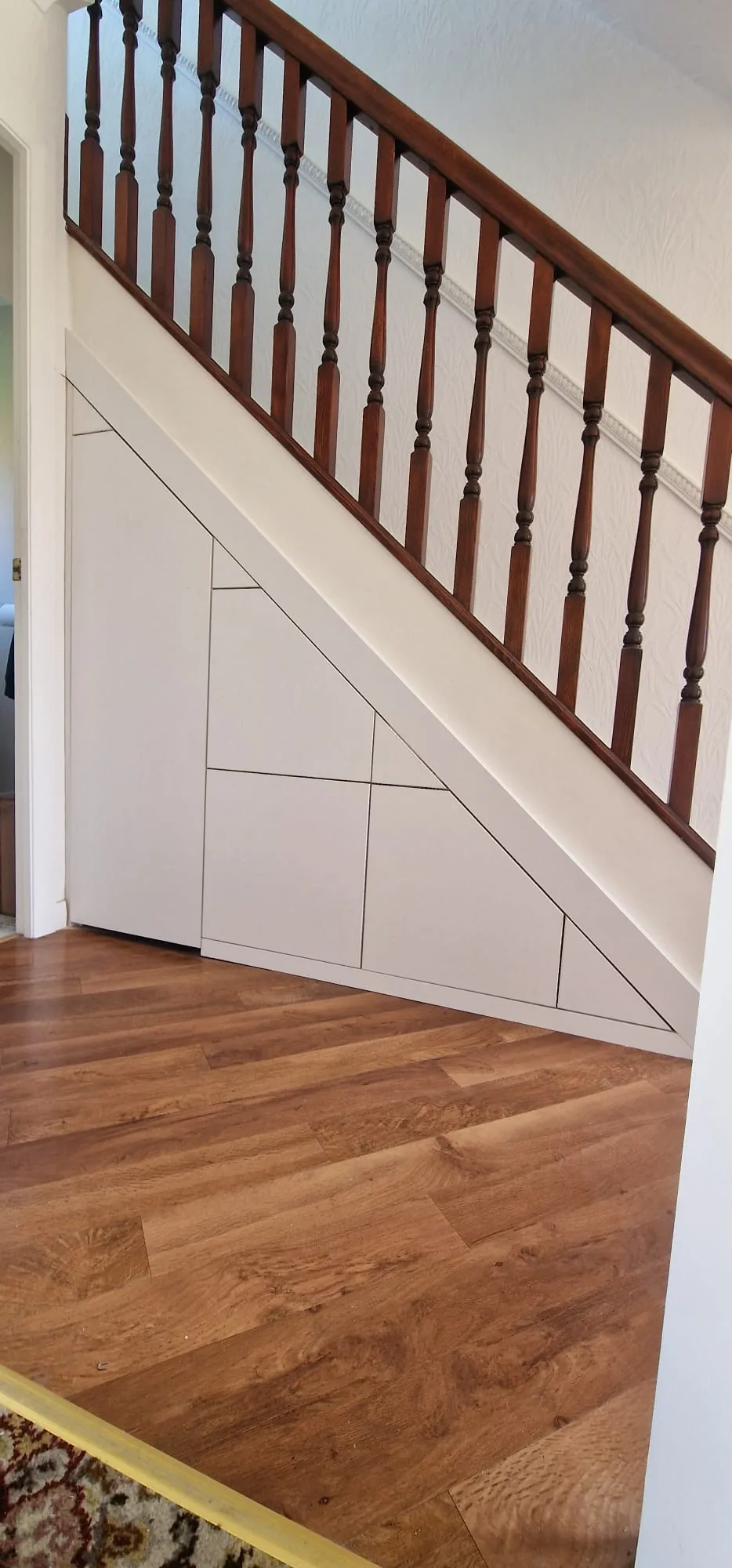 Cream handleless under stairs drawers with oak balustrade
