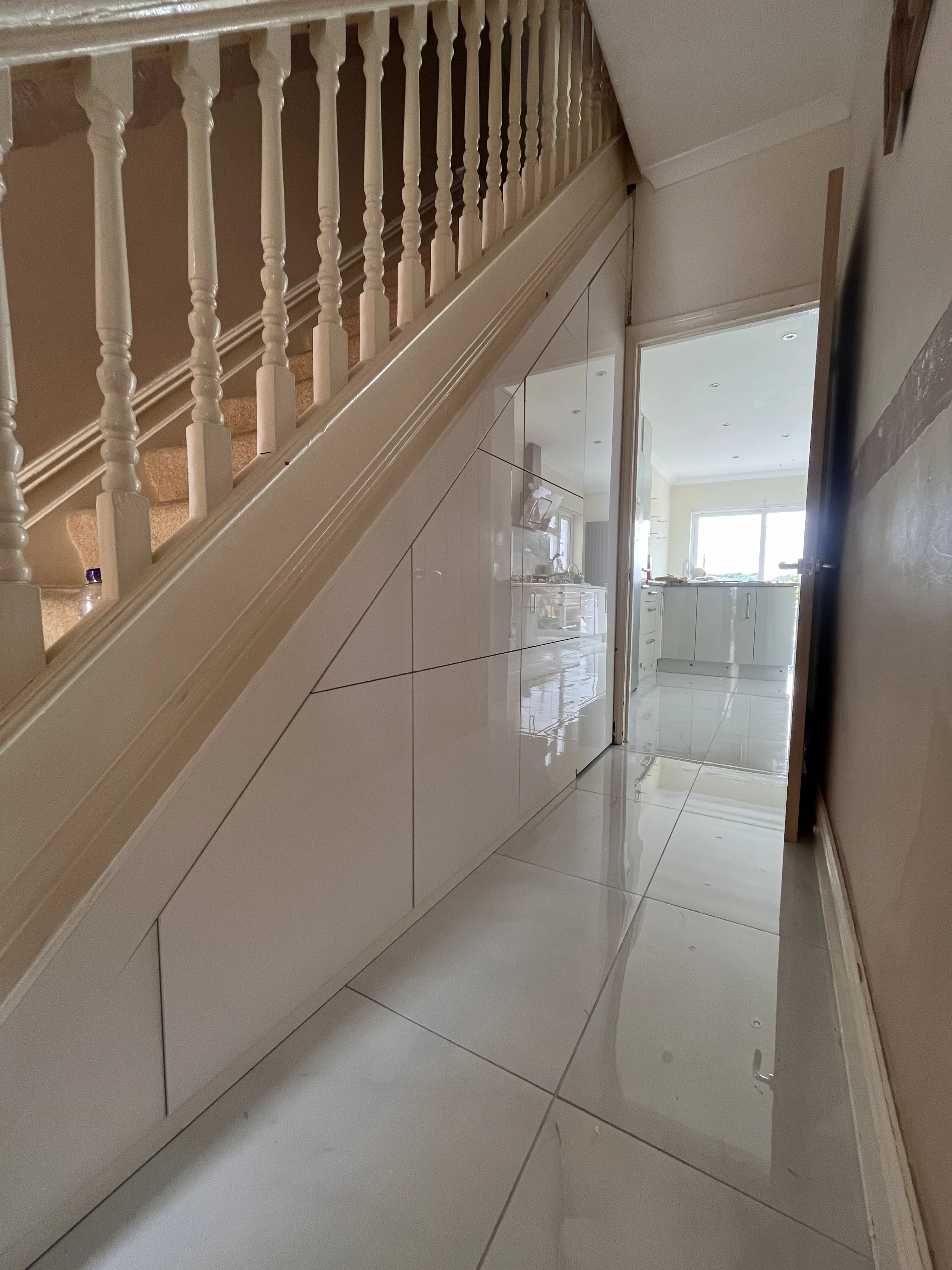 Under stairs storage with white cabinets beneath traditional staircase